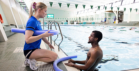 Learn to Swim instructor Lucy McCluskey talks to Ammanuel Akulu in the pool at his adult swimming lesson