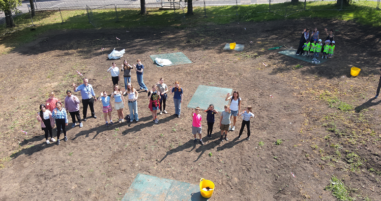 This aerial shot shows school pupils planting on the meadow site