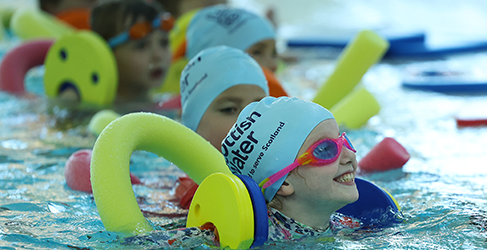 smiling kids using floats in pool